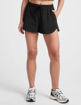 black shorts with a 2.5" inseam, encased elastic at waistband with drawcord, self binding at hem edges, side zipper pockets, and interior performance lining shorts.